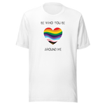 The image shows a unisex crew neck white t- shirt with a minimalist yet vibrant design. Centered on the front is a heart-shaped graphic filled with horizontal stripes in the colors of the progressive Pride flag, symbolizing inclusivity and diversity. Above the heart, the text reads "BE WHO YOU BE" and below it, "AROUND ME" both in sleek, black font. The design conveys an authenticity, making this t-shirt a wearable statement for equality and individuality.