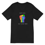 Black V-neck unisex t-shirt featuring a vibrant rainbow solidarity fist design in the center with white bold style text above "Hate Has" and the remaining text "No Home Here" directly below the fist. 
Emphasizing the power of inclusivity and love for all.